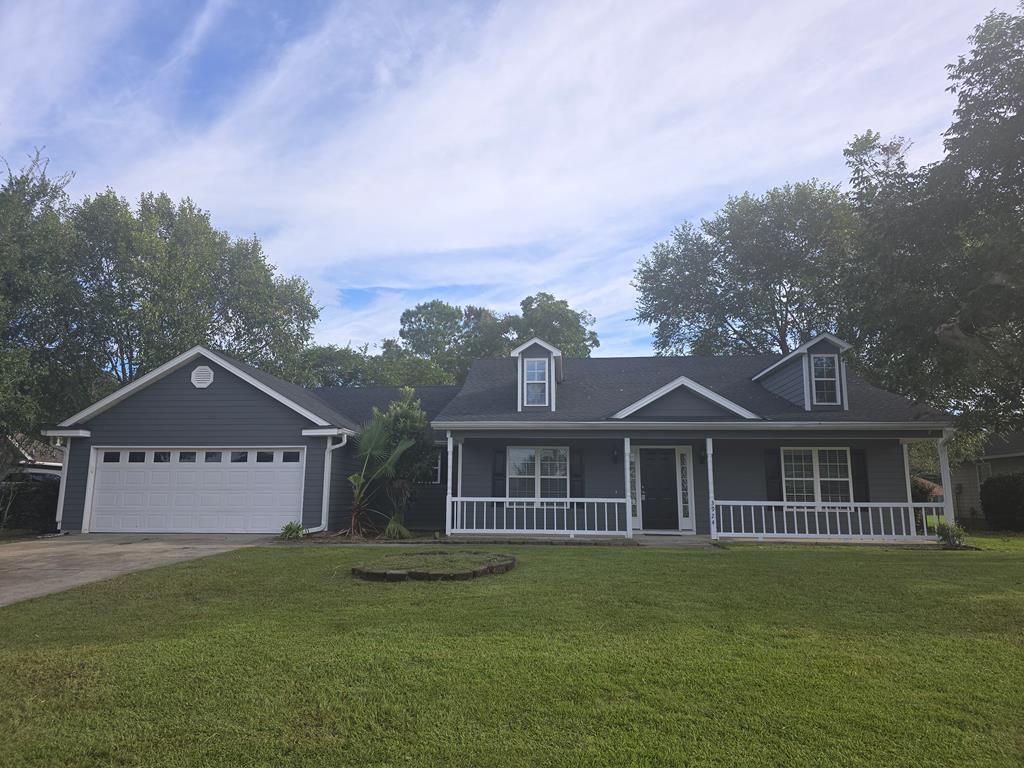 view of front of house with a porch, a garage, and a front lawn