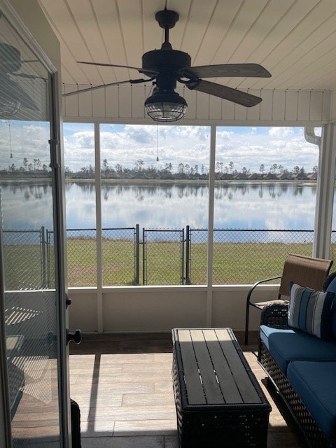 sunroom with ceiling fan, a water view, and plenty of natural light