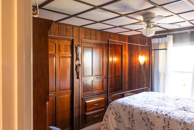 bedroom with a closet, ceiling fan, and wooden walls