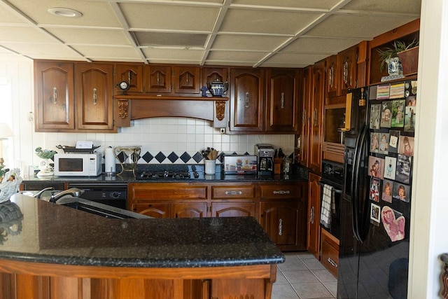 kitchen with black appliances, backsplash, light tile patterned floors, and sink