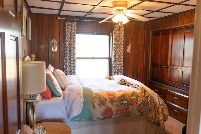 bedroom featuring ceiling fan, wooden walls, and a closet