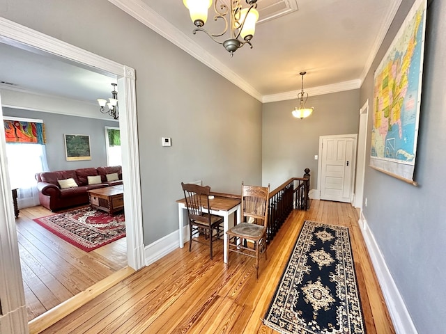 dining space with light wood-type flooring, ornamental molding, and a notable chandelier