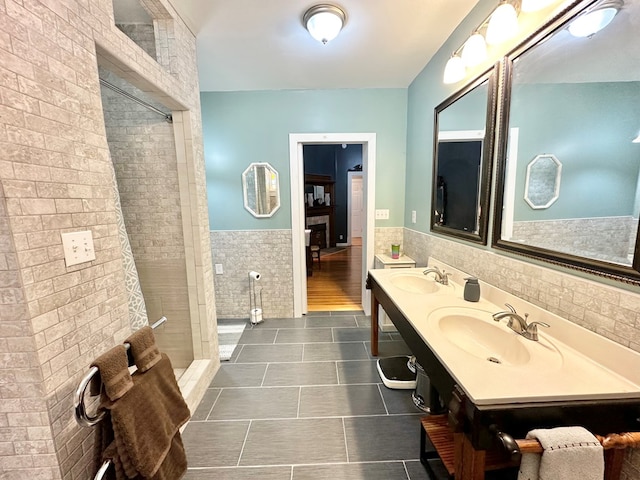 bathroom featuring a tile shower, tile walls, tile patterned floors, and vanity