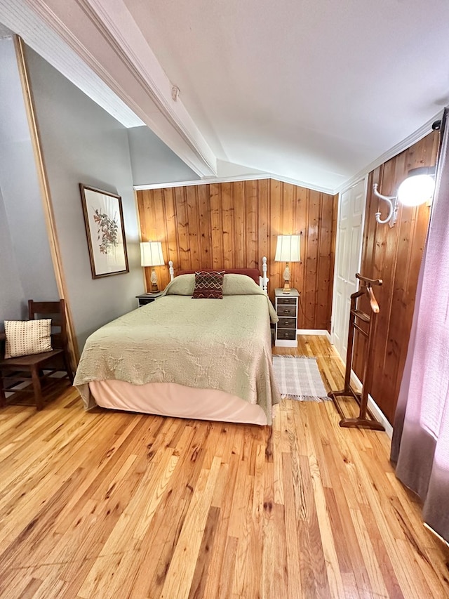 bedroom featuring light wood-type flooring, lofted ceiling, and wood walls