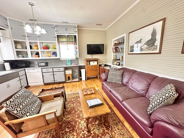 living room with a notable chandelier, ornamental molding, and light hardwood / wood-style floors