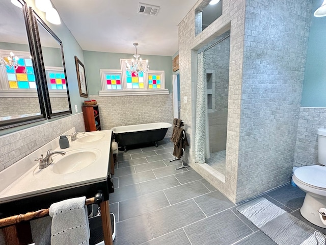 full bathroom featuring tile patterned flooring, tile walls, toilet, a notable chandelier, and independent shower and bath