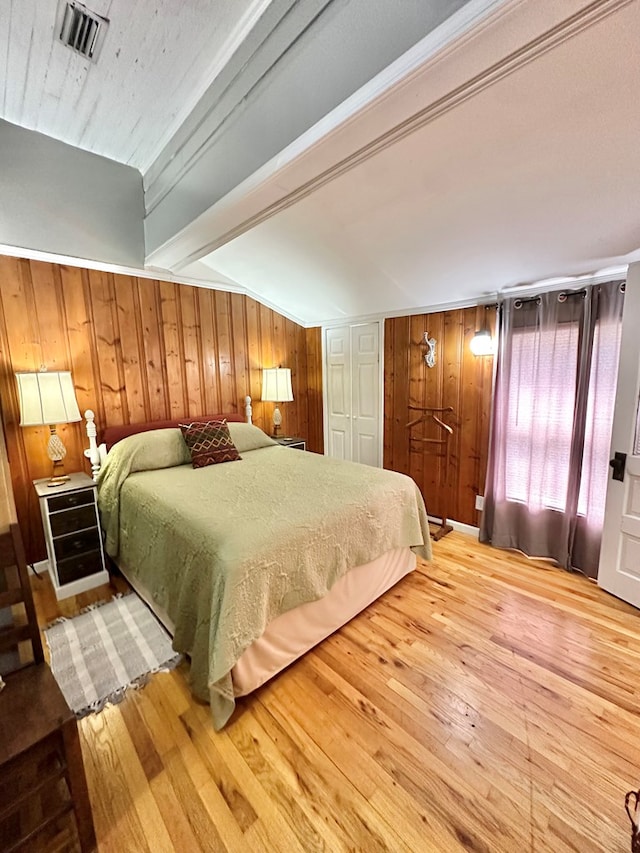 bedroom featuring hardwood / wood-style flooring, ornamental molding, wood walls, and beamed ceiling