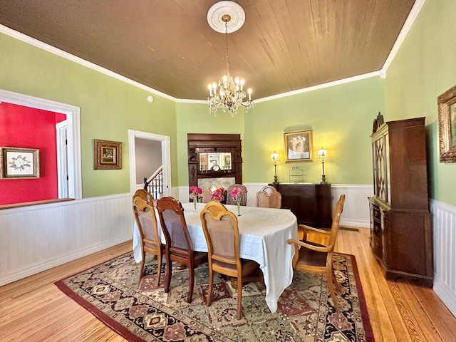 dining room with wood ceiling, ornamental molding, a chandelier, and light wood-type flooring