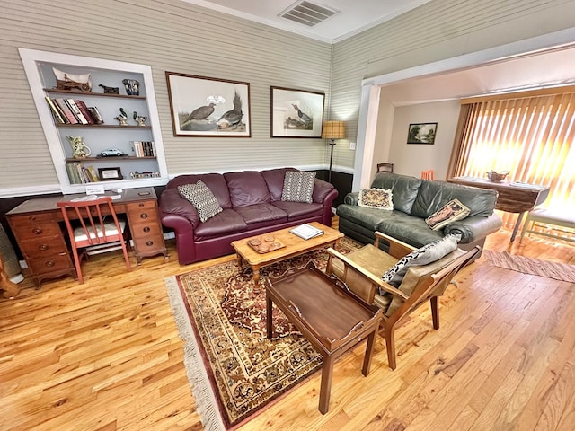 living room with built in features, ornamental molding, and hardwood / wood-style flooring