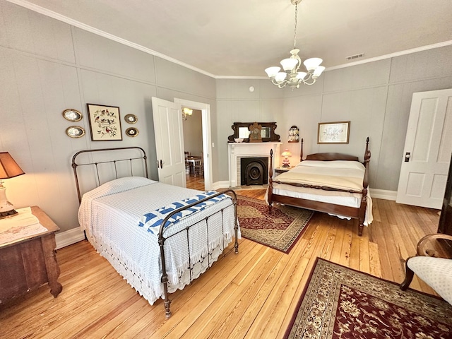 bedroom with light hardwood / wood-style floors, ornamental molding, and a notable chandelier