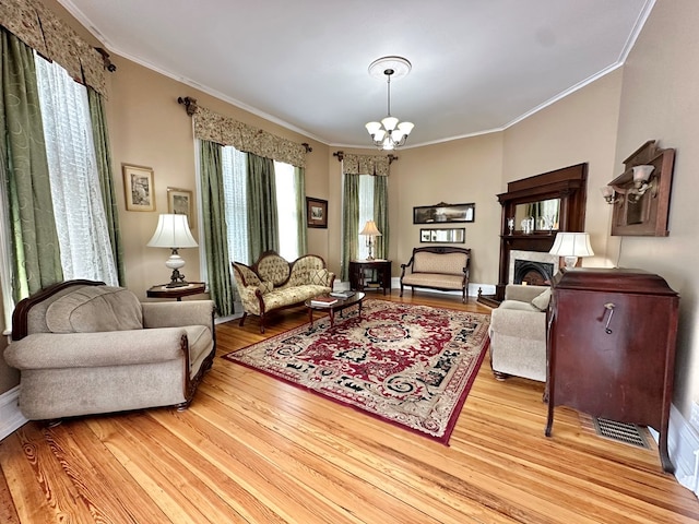 living room with crown molding, light wood-type flooring, and an inviting chandelier