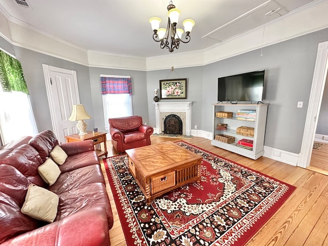 living room with wood-type flooring, a fireplace, an inviting chandelier, and ornamental molding