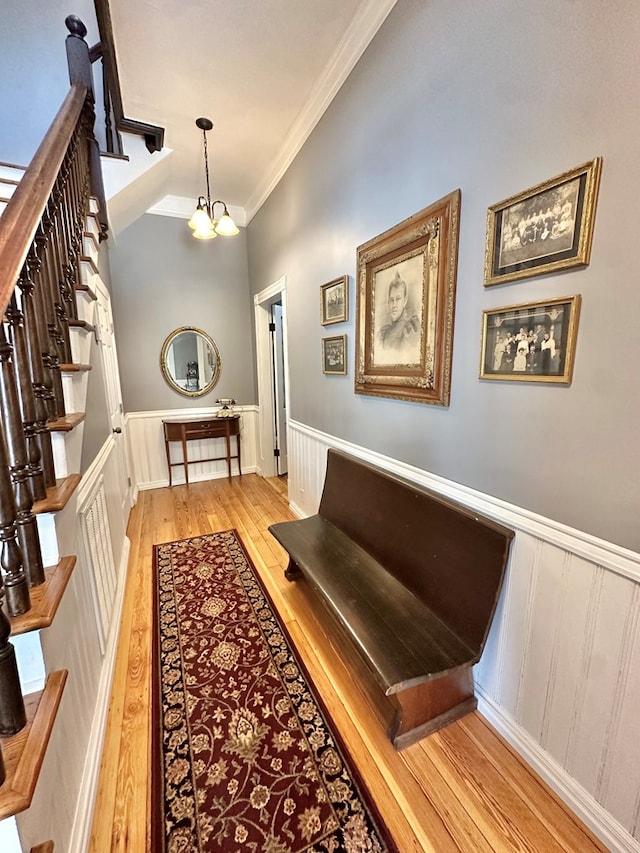 interior space featuring an inviting chandelier, ornamental molding, and light hardwood / wood-style floors