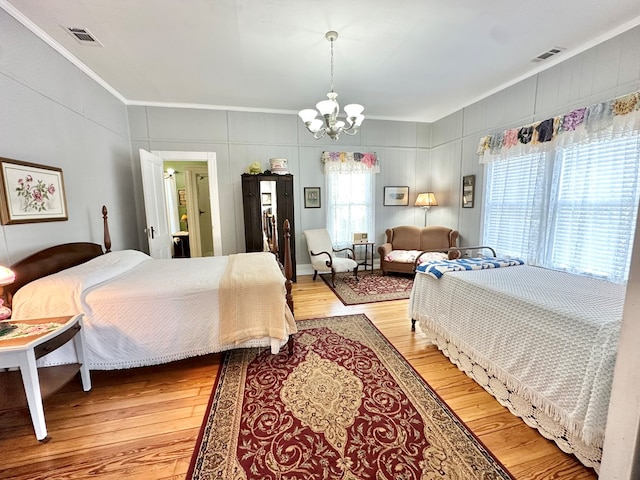 bedroom with light hardwood / wood-style flooring, crown molding, and a notable chandelier