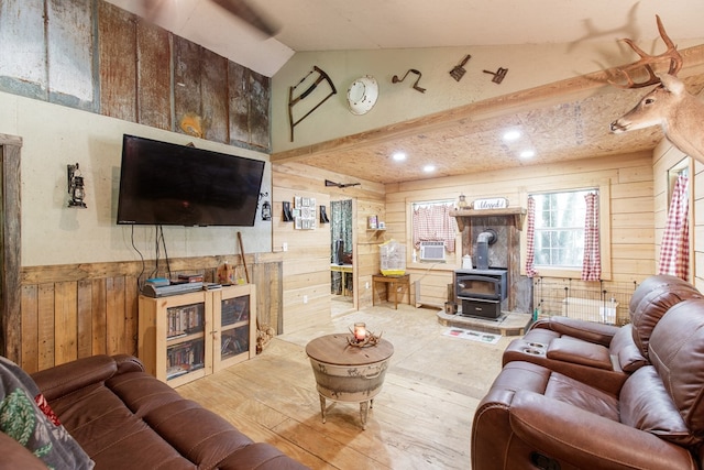 living room with a wood stove, wooden walls, light hardwood / wood-style flooring, and vaulted ceiling