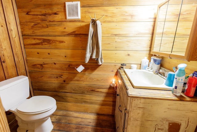 bathroom with wood walls, vanity, and toilet