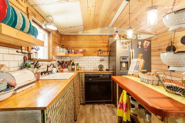 kitchen featuring sink, wood counters, light hardwood / wood-style flooring, vaulted ceiling, and wooden walls