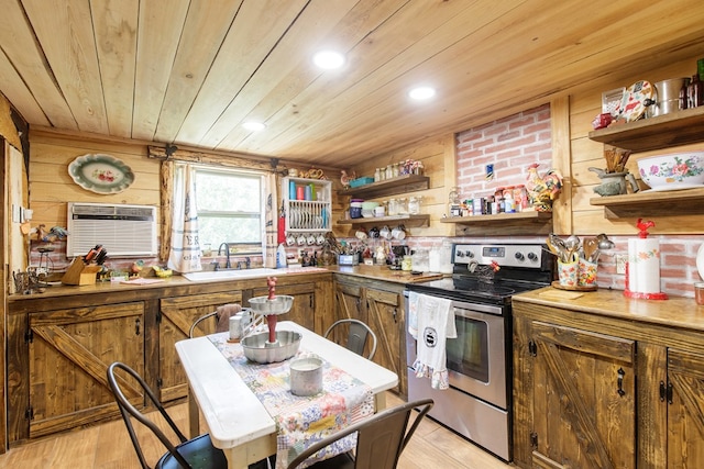 kitchen featuring wood walls, sink, stainless steel range with electric stovetop, and light wood-type flooring