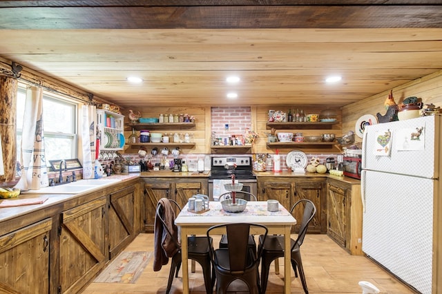 kitchen with light hardwood / wood-style floors, sink, stainless steel electric range, white fridge, and wood walls