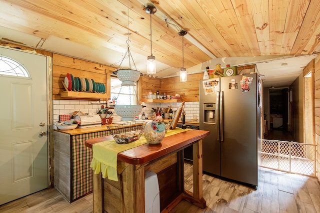 kitchen featuring stainless steel fridge with ice dispenser, plenty of natural light, and wooden walls