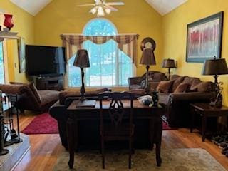 living room with ceiling fan, wood-type flooring, and vaulted ceiling