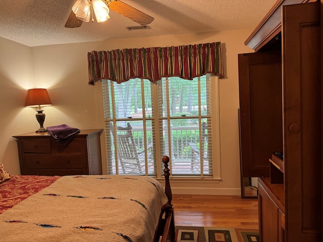 bedroom with multiple windows, hardwood / wood-style floors, a textured ceiling, and ceiling fan