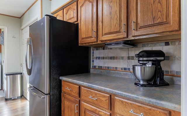 kitchen featuring backsplash, stainless steel fridge, ornamental molding, and light hardwood / wood-style floors