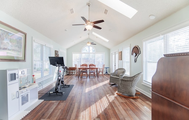 workout area with a textured ceiling, ceiling fan, hardwood / wood-style flooring, and lofted ceiling with skylight