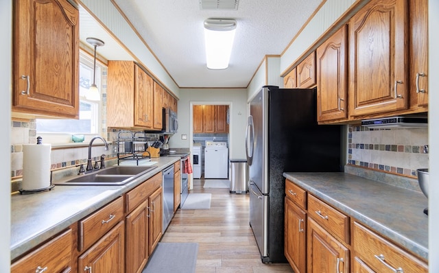 kitchen featuring washer and clothes dryer, stainless steel appliances, decorative backsplash, hanging light fixtures, and sink