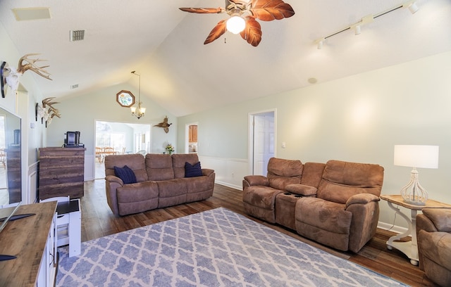 living room with ceiling fan with notable chandelier, dark wood-type flooring, rail lighting, and vaulted ceiling