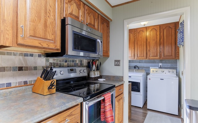 kitchen with crown molding, stainless steel appliances, independent washer and dryer, and tasteful backsplash