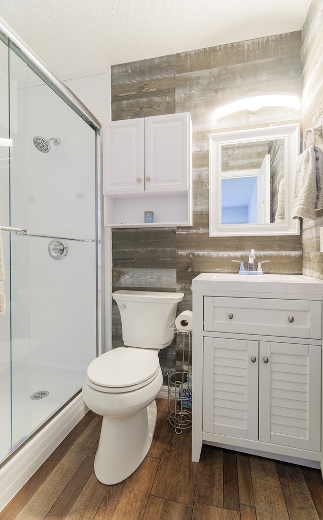 bathroom with toilet, vanity, a shower with door, and hardwood / wood-style floors