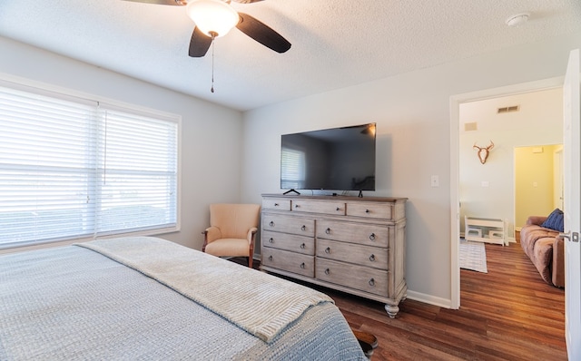 bedroom with ceiling fan, dark wood-type flooring, and a textured ceiling