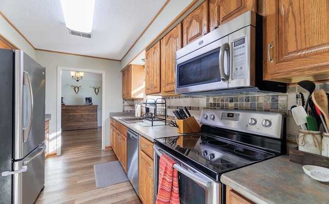 kitchen with tasteful backsplash, light hardwood / wood-style floors, sink, stainless steel appliances, and a chandelier