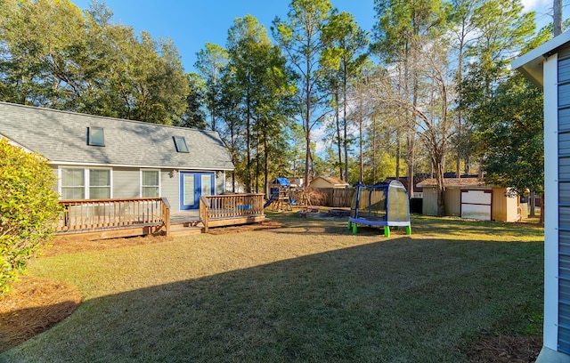 view of yard with a playground, a trampoline, a deck, and a storage unit