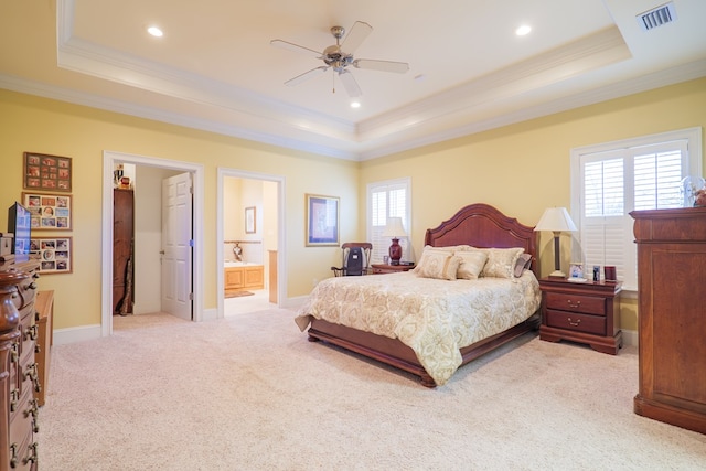 carpeted bedroom with ornamental molding, ensuite bath, ceiling fan, and a raised ceiling