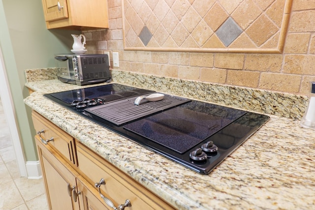 kitchen with black electric cooktop, light stone counters, and light tile patterned floors