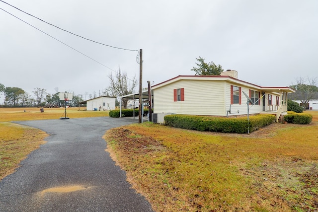 view of home's exterior featuring central air condition unit, a yard, a carport, and covered porch