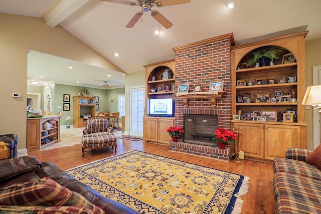 living room with lofted ceiling with beams, a fireplace, ceiling fan, and built in shelves