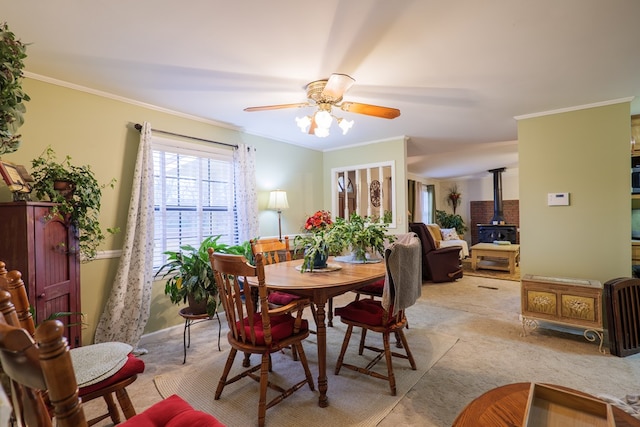 dining area with ceiling fan, crown molding, and a wood stove