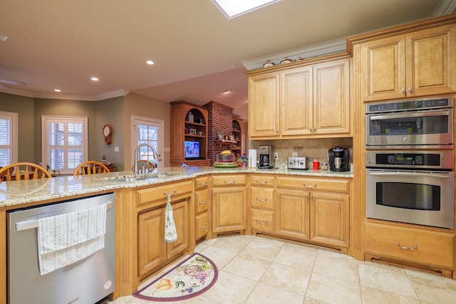 kitchen with kitchen peninsula, appliances with stainless steel finishes, ornamental molding, and sink