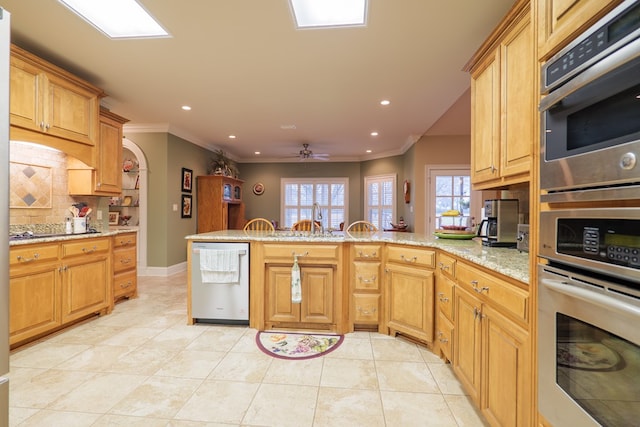 kitchen featuring decorative backsplash, ceiling fan, kitchen peninsula, and appliances with stainless steel finishes