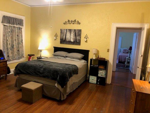 bedroom with crown molding and dark wood-type flooring