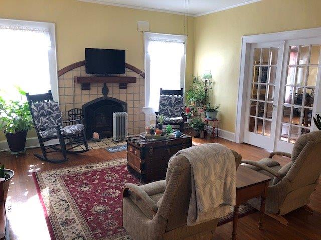 living room with hardwood / wood-style floors, a fireplace, ornamental molding, and radiator heating unit