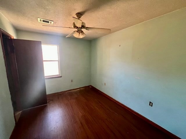 unfurnished room with ceiling fan, dark hardwood / wood-style flooring, and a textured ceiling