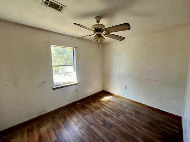 empty room featuring dark wood-type flooring and ceiling fan