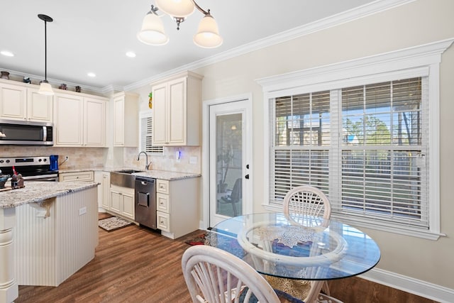 kitchen with dark wood-type flooring, stainless steel appliances, light stone counters, pendant lighting, and ornamental molding