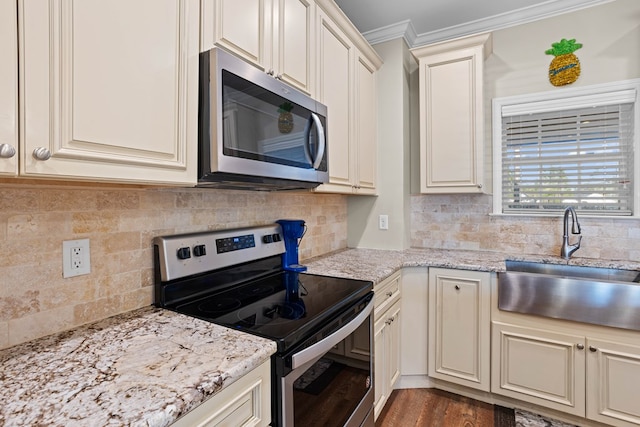 kitchen featuring hardwood / wood-style floors, cream cabinets, crown molding, sink, and stainless steel appliances