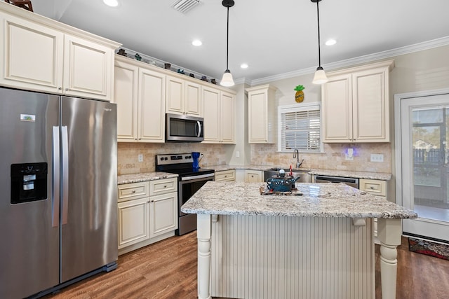 kitchen with hanging light fixtures, appliances with stainless steel finishes, a kitchen island, and plenty of natural light