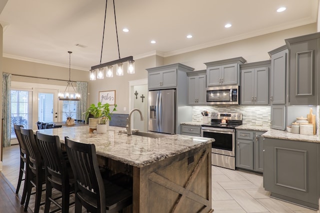 kitchen with a breakfast bar area, light stone countertops, ornamental molding, a large island, and stainless steel appliances